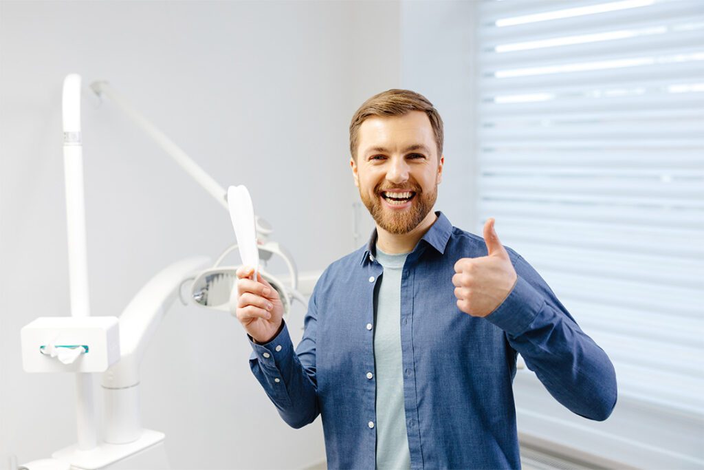 Dental patient holding mirror and making a thumbs up gesture