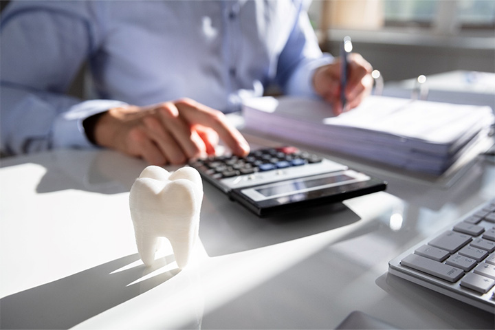 A model tooth in front of a businessperson calculating costs