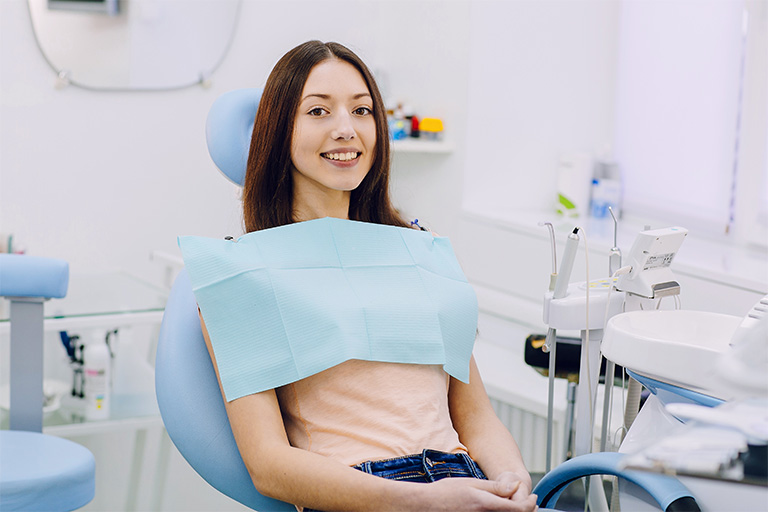 Woman sitting in dental chair and smiling