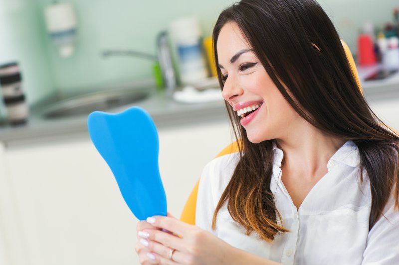 A young woman admiring the results of her smile makeover treatment