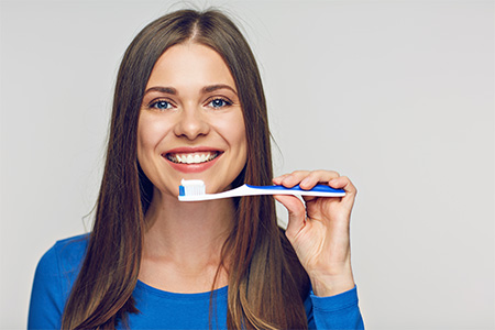 Woman in blue shirt holding a toothbrush