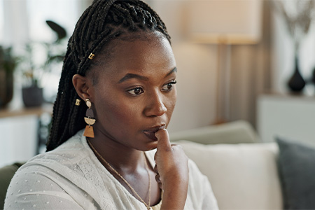 Woman sitting on couch biting her fingernail