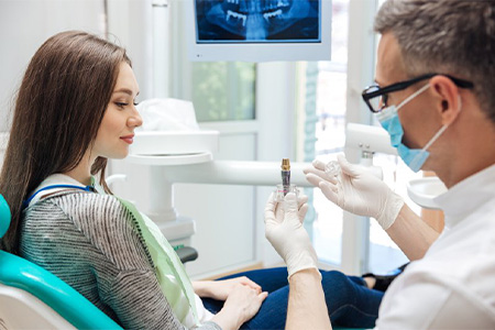 Dentist showing dental implant model to patient