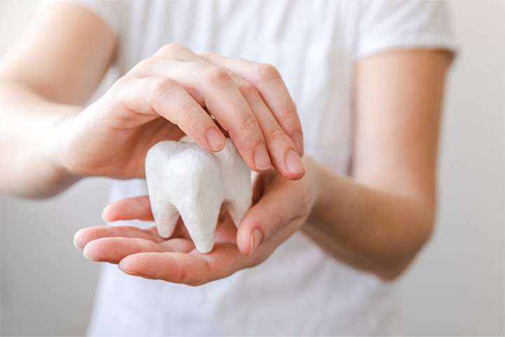 Patient holding a giant plaster model of a tooth