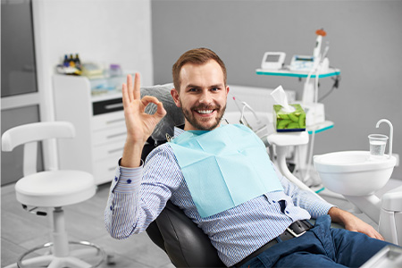 Man in dental chair giving an okay sign