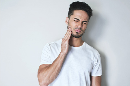 Man holding his jaw and cringing in pain