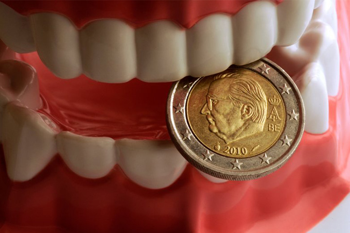 Model of white teeth biting coin.