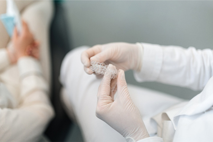 Dentist holding clear aligners during appointment.