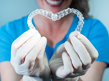 Dentist holding two clear Invisalign aligners.