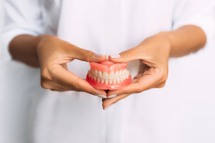 Lady presents viewer with dentures.